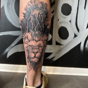 Unterschenkel mit schwarzgrauem Löwen-Tattoo